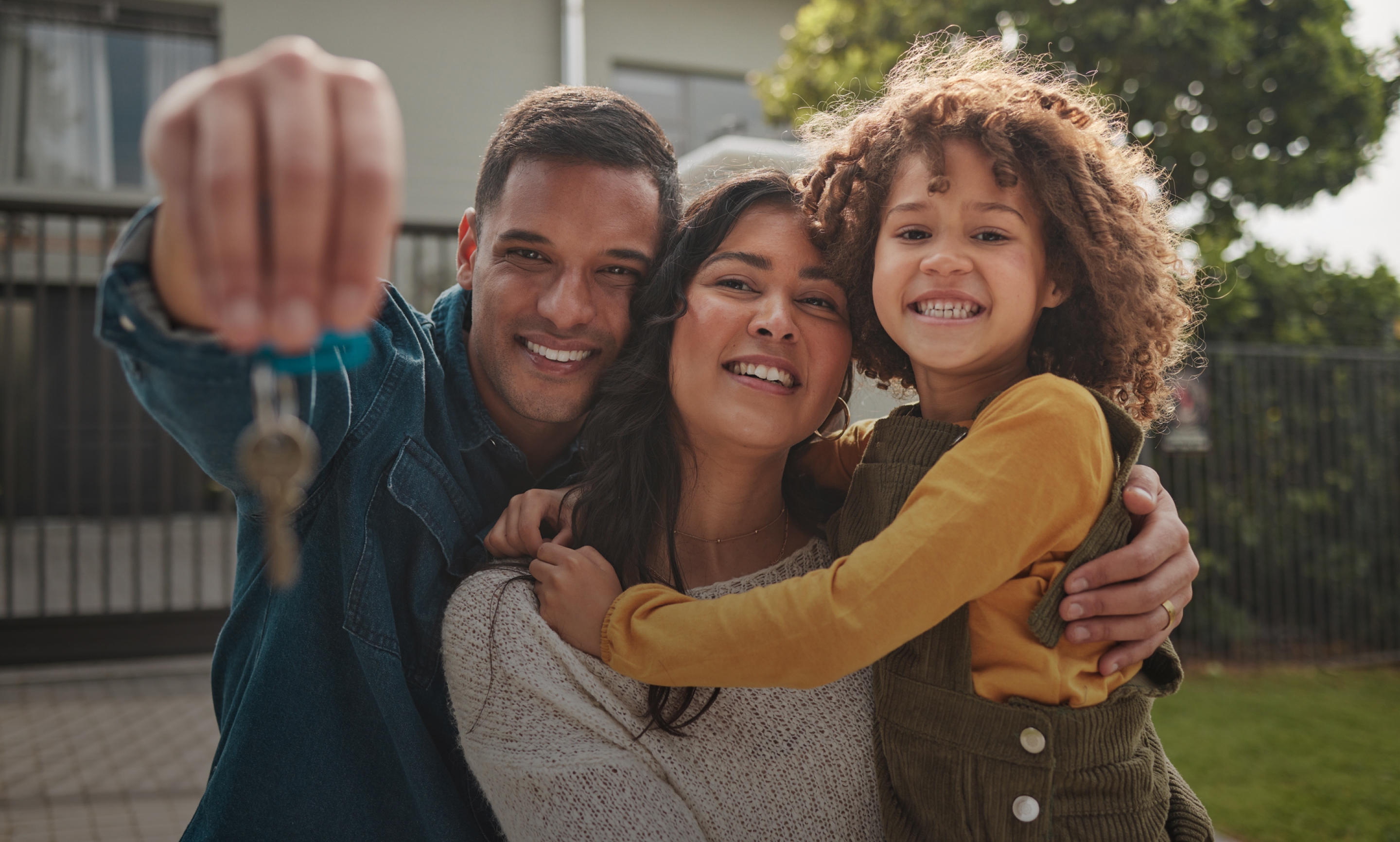 Happy family holding keys in front of their new home.